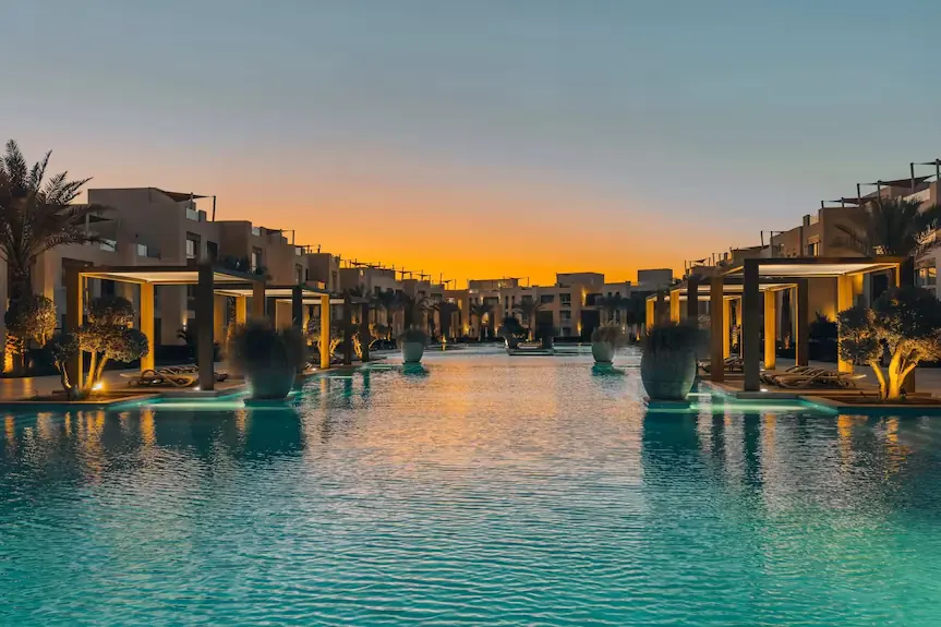 Pool at Mangroovy Residences glowing at sunset with palm-lined cabanas